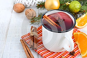 Hot mulled wine in a mug on a white wooden background. A traditional warming winter wine drink with aromatic spices