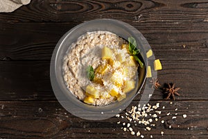 Hot oatmeal with fresh mango pieces, cooked in milk and garnished with mint chanterelles. Healthy diet vegetarian breakfast