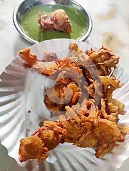 Hot onion bhajjiya bhajiya Indian fast food street food with green pudina chutney on paper plate ready to eat yummy tastey food