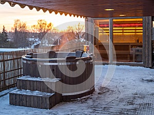 Hot outdoor wooden bath tub on terrace of private house. Finnish sauna