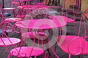 Hot pink metal tables and chairs out on brick sidewalk