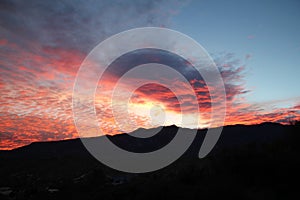 Hot pink and orange cotton candy dawn clouds over the mountains in Tucson Arizona