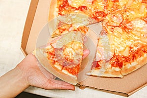 Hot pizza slice with melting cheese on a rustic wooden table