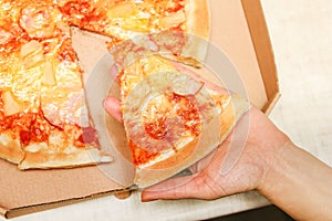 Hot pizza slice with melting cheese on a rustic wooden table