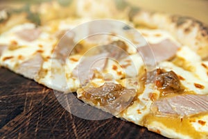 Hot pizza slice with melting cheese on a rustic wooden table