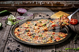 Hot pizza slice with melting cheese on a rustic wooden table. copy text recipe