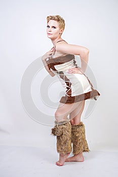 Hot plus size woman in fur carnival costume of primitive man on white background in Studio. a beautiful savage girl in a brown dre