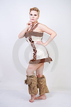 Hot plus size woman in fur carnival costume of primitive man on white background in Studio. a beautiful savage girl in a brown dre