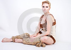 Hot plus size woman in fur carnival costume of primitive man on white background in Studio. a beautiful savage girl in a brown dre