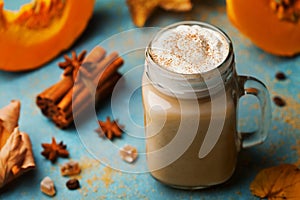 Hot pumpkin spiced latte or coffee in cup decorated cinnamon on blue vintage background. Autumn, fall or winter drink.