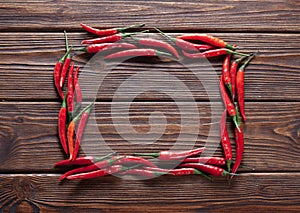 Hot red chilli pepper in pods  in the shape of a rectangle on wooden table