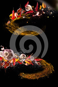 Hot red pepper, garlic, different spices powder flying on a black background Motion freeze photo composition