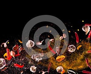 Hot red pepper, garlic, different spices powder flying on a black background Motion freeze photo composition