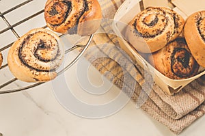 hot rolls with poppy/fresh rolls with poppy on a metal lattice and in a wooden box on a white table. Top view