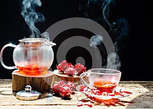 Hot roselle tea is poured from a kettle into glass cup with steam. Organic and Summer drink photo