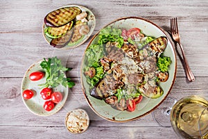 Hot salad with veal, mushrooms, salad leaves, eggplant, zucchini, tomatoes, garnished with grated almonds and Parmesan cheese