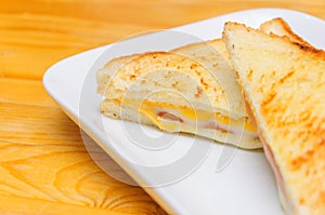 Hot sandwich with ham cheese on the dishe with wood background