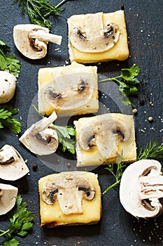 Hot sandwiches with cheese and mushrooms, greens, on a dark stone background, top view, selective focus