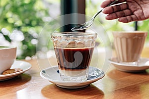 Hot served Vietnamese coffee that can wake you up: Black coffee mix with condense milk in clear glass served on wooden table