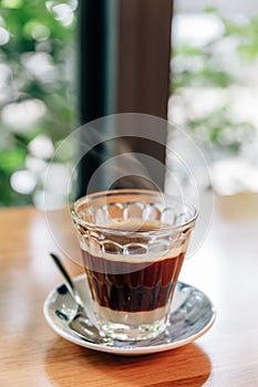 Hot served Vietnamese coffee that can wake you up: Black coffee mix with condense milk in clear glass served on wooden table.