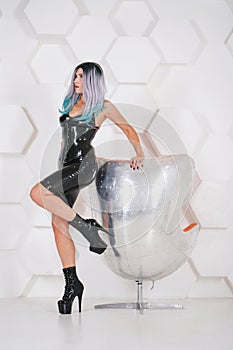 Hot sexual woman wearing latex rubber alternative costume on white studio futuristic background