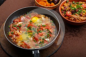 hot shakshuka in a frying pan sprinkled with green onions on the Shabbat table.