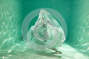 Hot Slim Woman Posing Under water in beautiful clothes alone in the deep