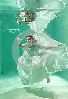 Hot Slim Woman Posing Under water in beautiful clothes alone in the deep