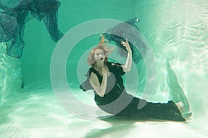 Hot Slim Woman Posing Under water in beautiful clothes alone in the deep