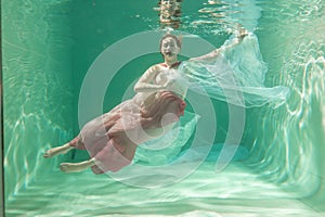 Hot Slim Woman Posing Under water in beautiful clothes alone in the deep