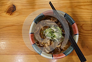 Hot soba with deep fried egg with onion in Japanese bowl on timber table