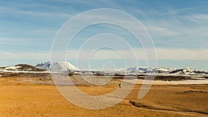 Hot soil in geothermic area surrounded by snowy mountains in North Iceland