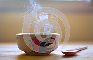Hot soup in bowl with smoke on wood table. photo
