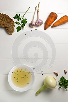 Fresh bouillon in a white plate with finely chopped herbs with ingredients and croutons on a white background. photo