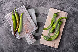 Hot spicy green chili peppers on wooden cutting boards, stone concrete background