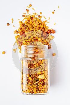 Hot spicy Nav Ratan snacks spilled out and in a glass jar, made with red chili, peanuts, corn flakes. photo