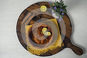 Hot and spicy sauce with lime on wooden board against white background