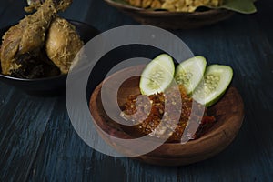 Hot and spicy sauce with sliced cucumber on wooden board