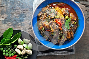 Hot and spicy stir - fried ell in bowl on old rustic wooden table.