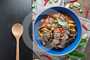 Hot and spicy stir - fried ell in bowl on old rustic wooden table.