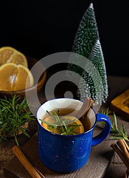 Hot spicy warming herbal tea in blue cup. Tea with orange and rosemary. Selective focus, blurred background