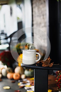 Hot Steaming Coffee on Chair on Front Porch Decorated for Autumn