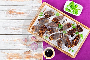 Hot sticky ribs on parchment paper on chopping board