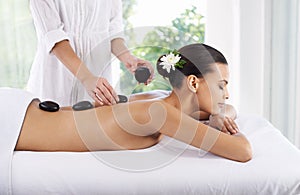 Hot stone healing. A young woman receiving a hot stone massage.
