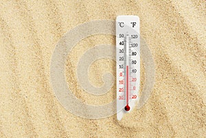 Hot summer day. Celsius and fahrenheit scale thermometer in the sand. Ambient temperature plus 13