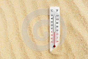 Hot summer day. Celsius and fahrenheit scale thermometer in the sand. Ambient temperature plus 2