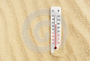 Hot summer day. Celsius and fahrenheit scale thermometer in the sand. Ambient temperature plus 27