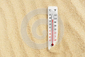 Hot summer day. Celsius and fahrenheit scale thermometer in the sand. Ambient temperature plus 37