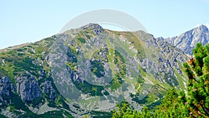Horúci letný deň so svetlomodrým oparom. Horská krajina s mohutnými skalnatými svahmi Vysokých Tatier na Slovensku