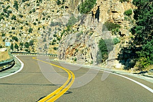 Hot summer road in hills and mountains of arizona for vehicle and car transportation with metal gaurd rail or rock faces photo